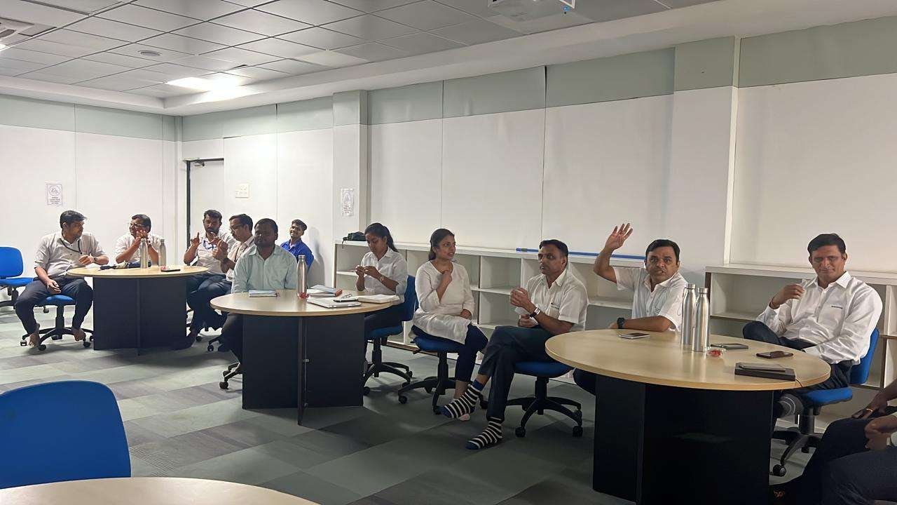 An interactive training session with participants engaged in a discussion, some using sign language.