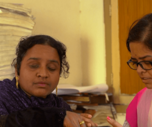 Visually impaired woman using a smartphone with assistance, showcasing digital inclusion through Youth4Jobs' VI Connect program.